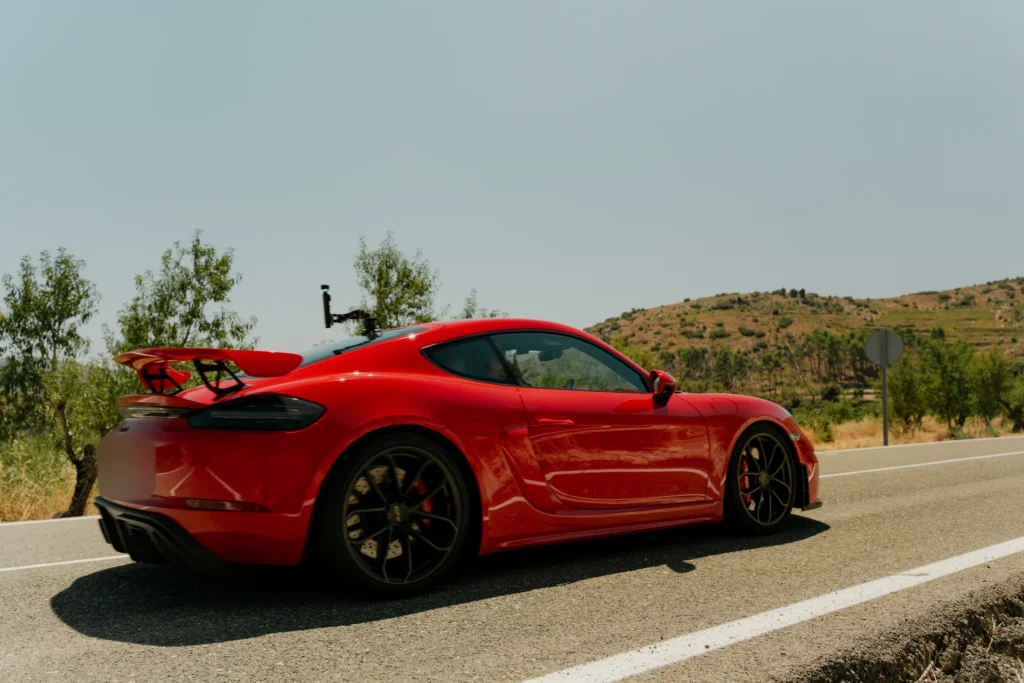 Porsche 718 GT4 RS rojo en carretera de montaña en la ruta RX01 Serranías del Turia de Road Experience, ruta en coche deportivo por Valencia