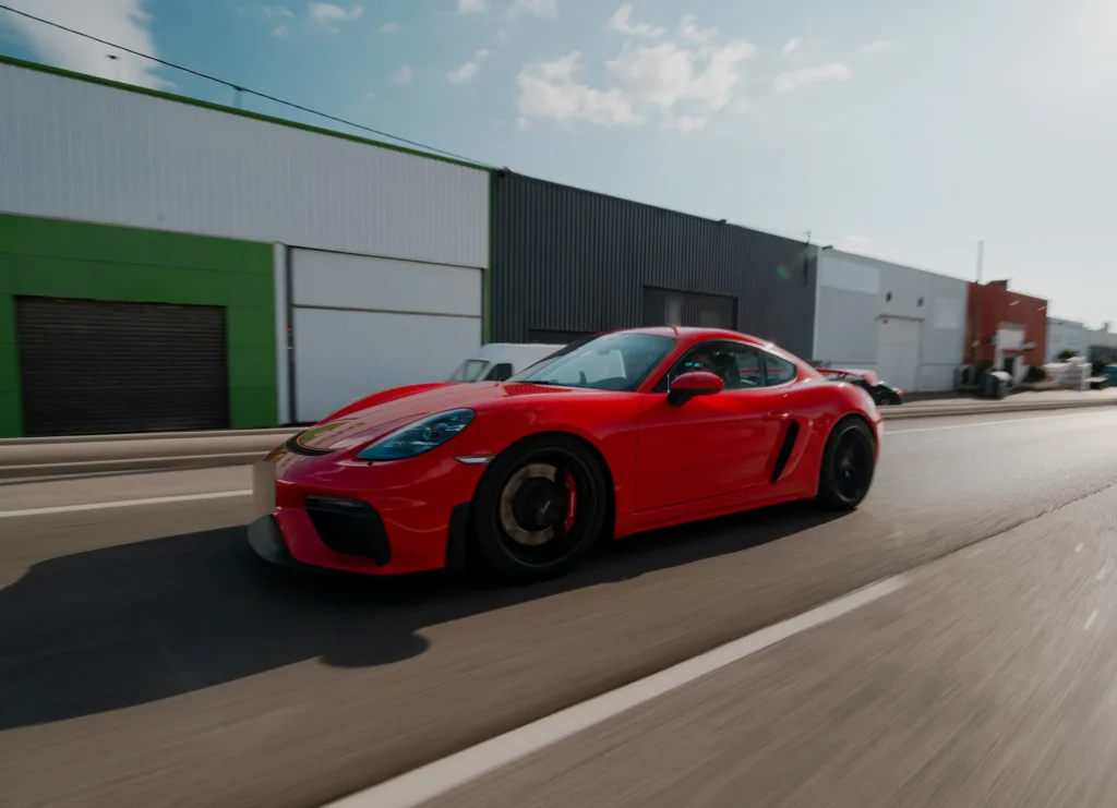 Porsche 718 Cayman GT4 rojo en carretera en la ruta RX02 Vistabella de Road Experience, ruta en coche deportivo por Castellón