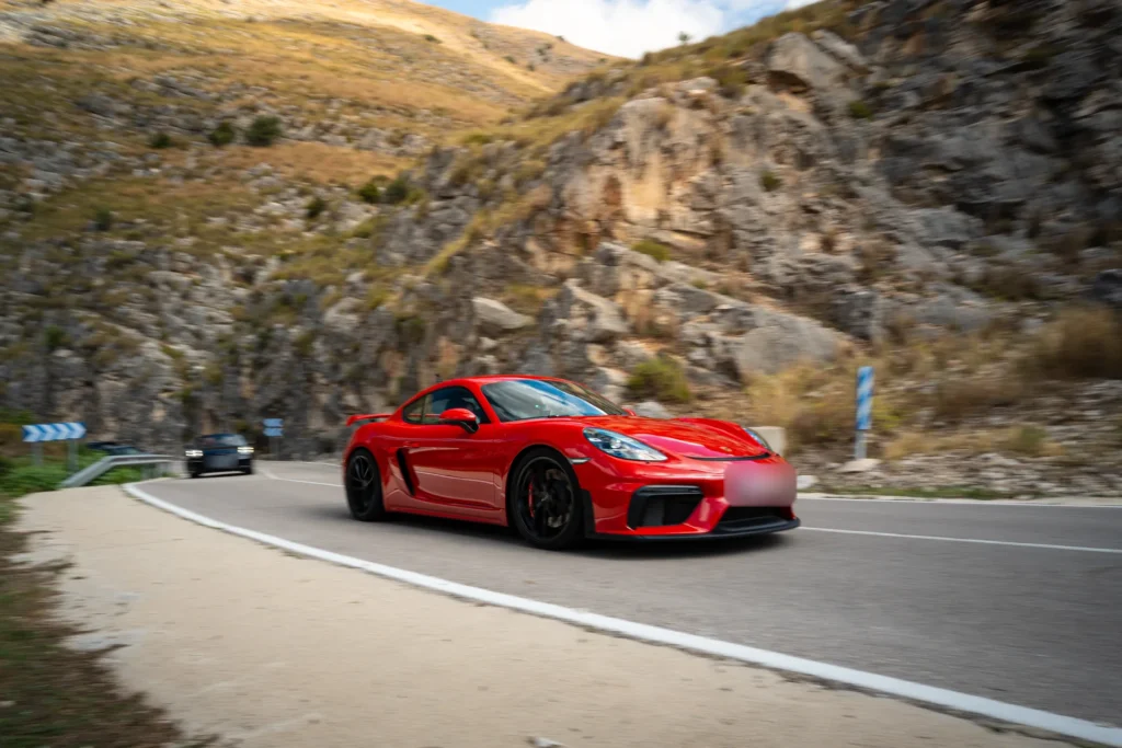 Porsche 718 Cayman GT4 rojo en curva de montaña en la ruta RX03 El Santuario de Road Experience, ruta en coche deportivo por Alicante